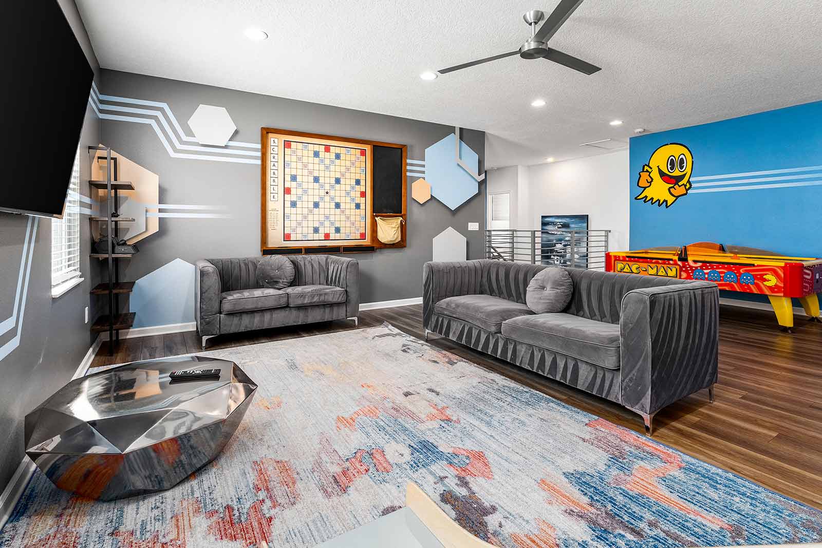 game loft with gray couches, wall scrabble, and air hockey table