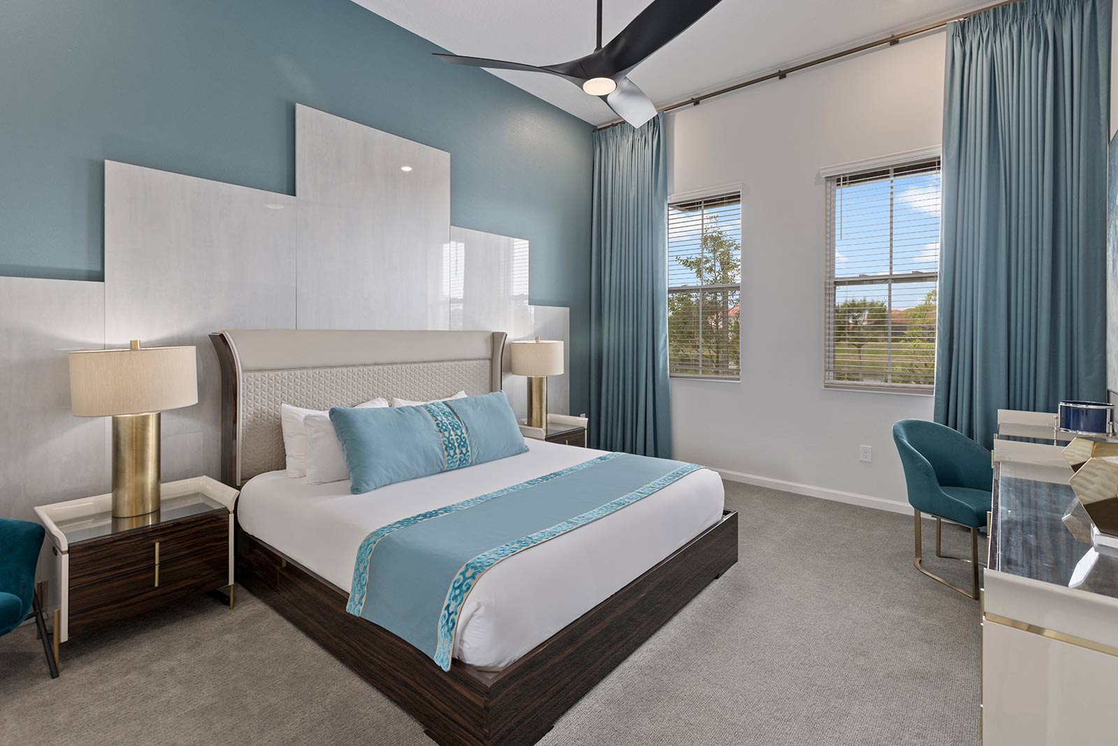 bedroom with light blue bedding on king bed and curtains