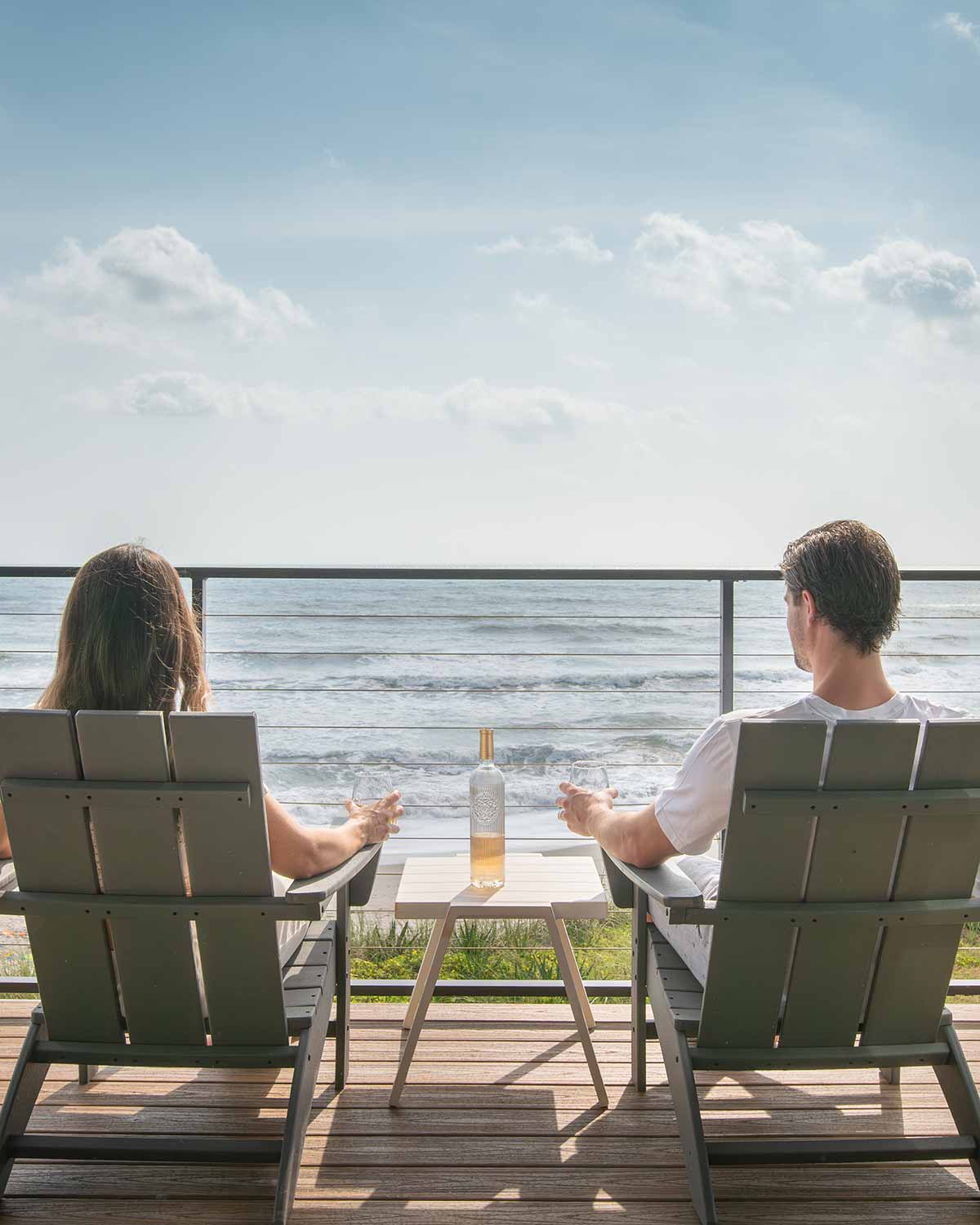 couple sitting on a balcony with drinks overlooking the ocean