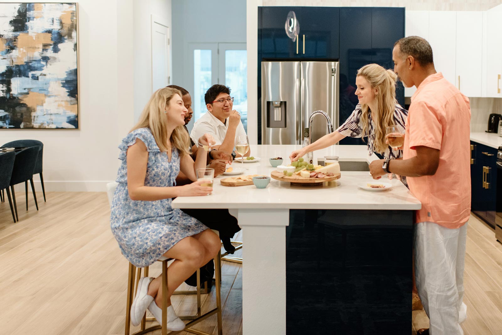 group of people eating appetizers around a kitchen island