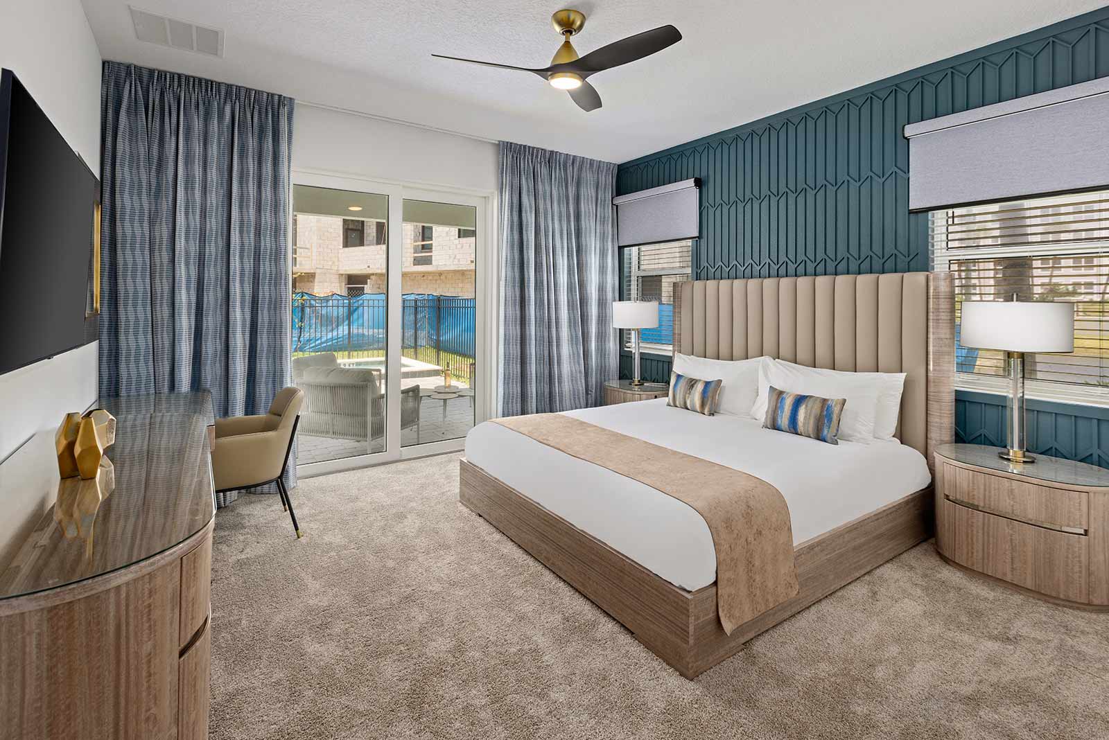 bedroom with patterned blue wall with king bed and desk