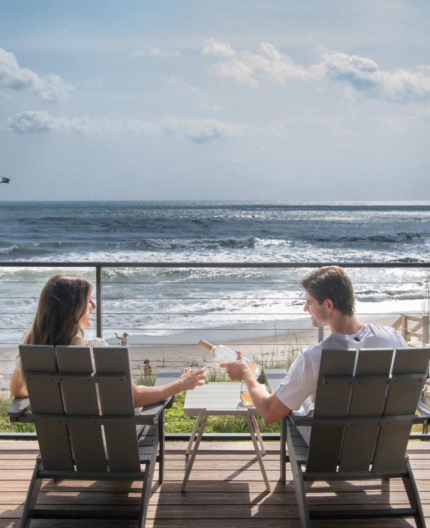 couple sitting on the beach drinking wine