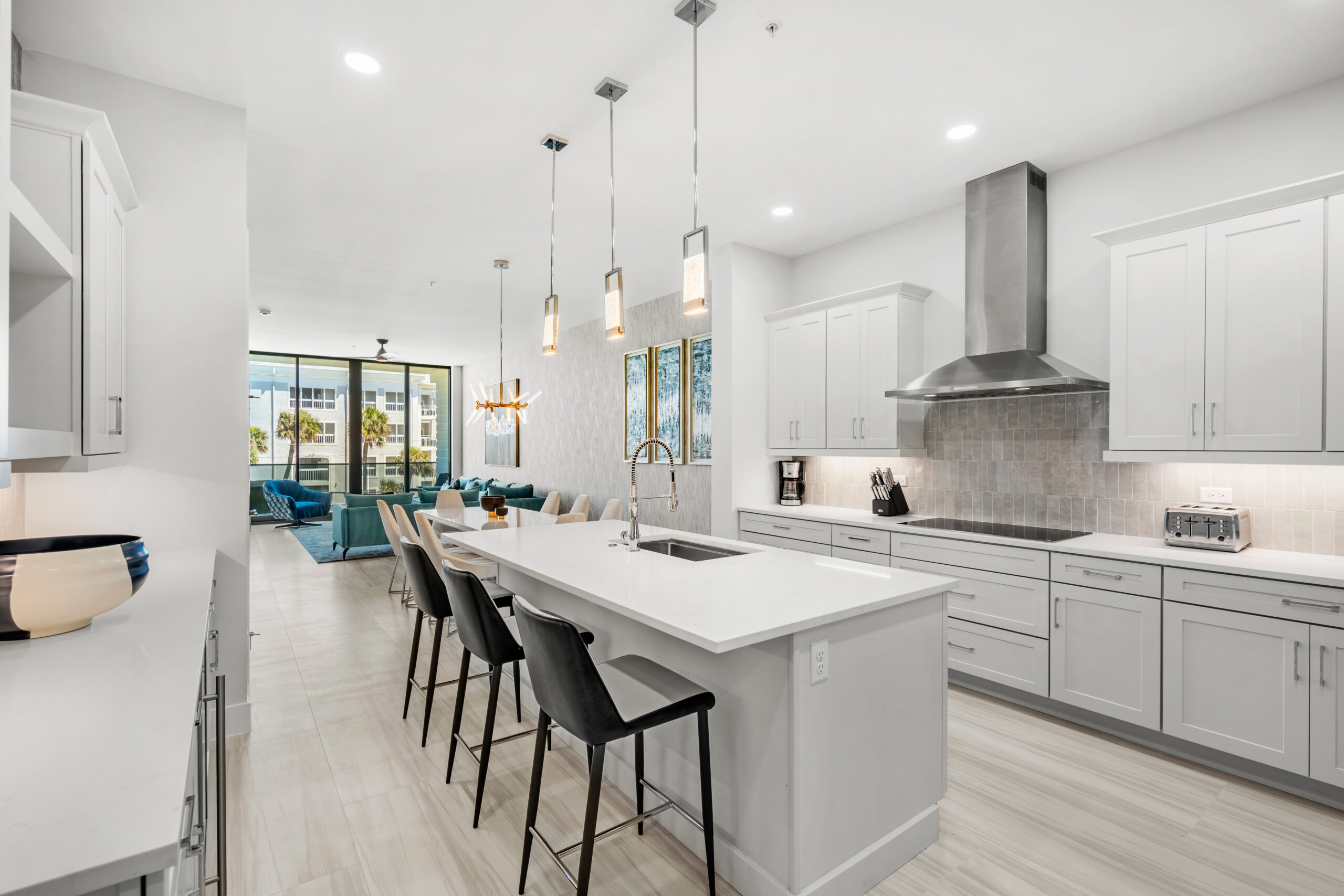 kitchen with island and 3 stools next to living room