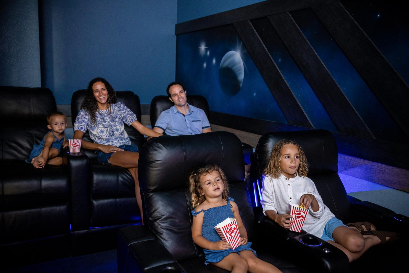 parents and 2 daughters watching tv in a theater