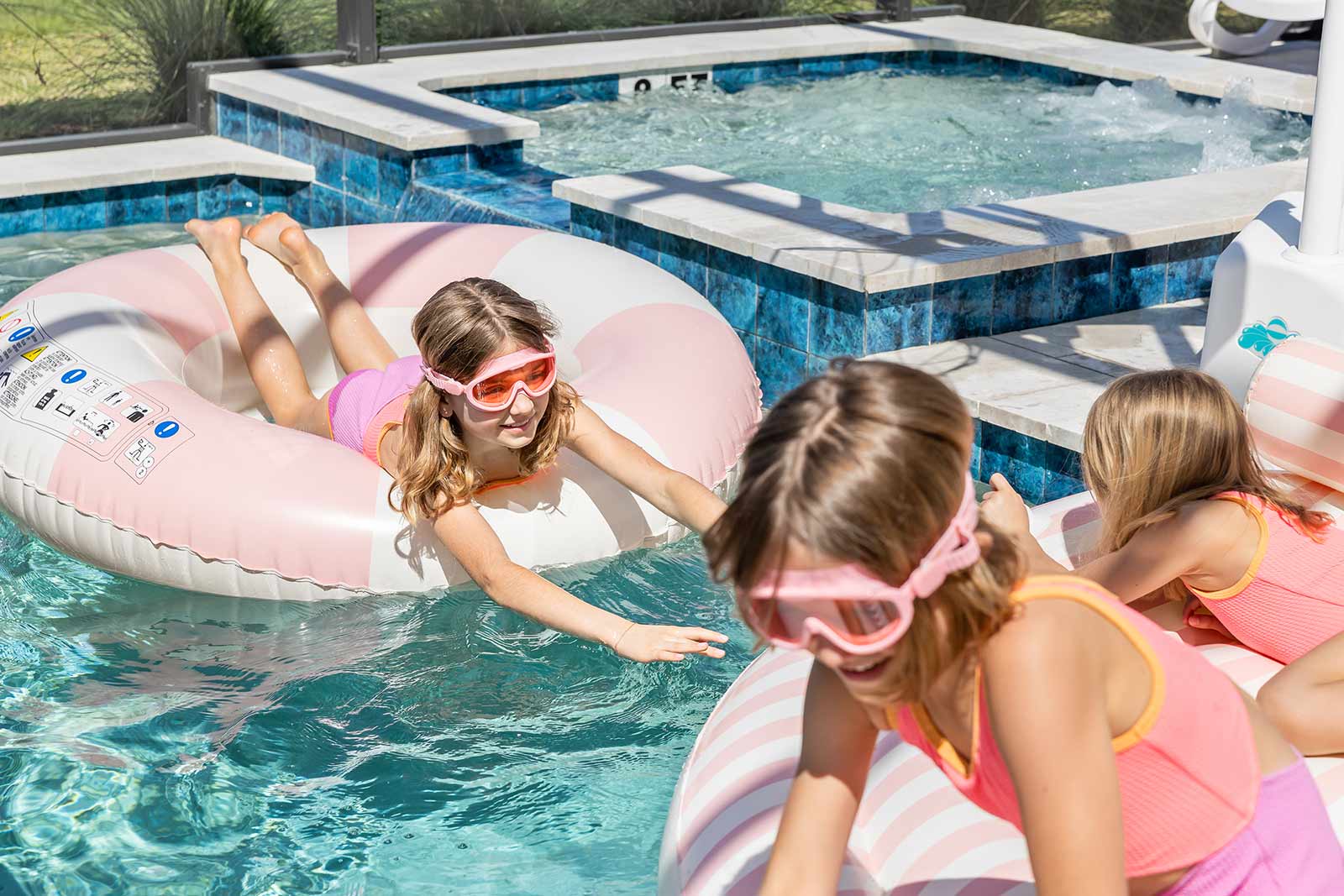 girls playing in a backyard pool in innertubes